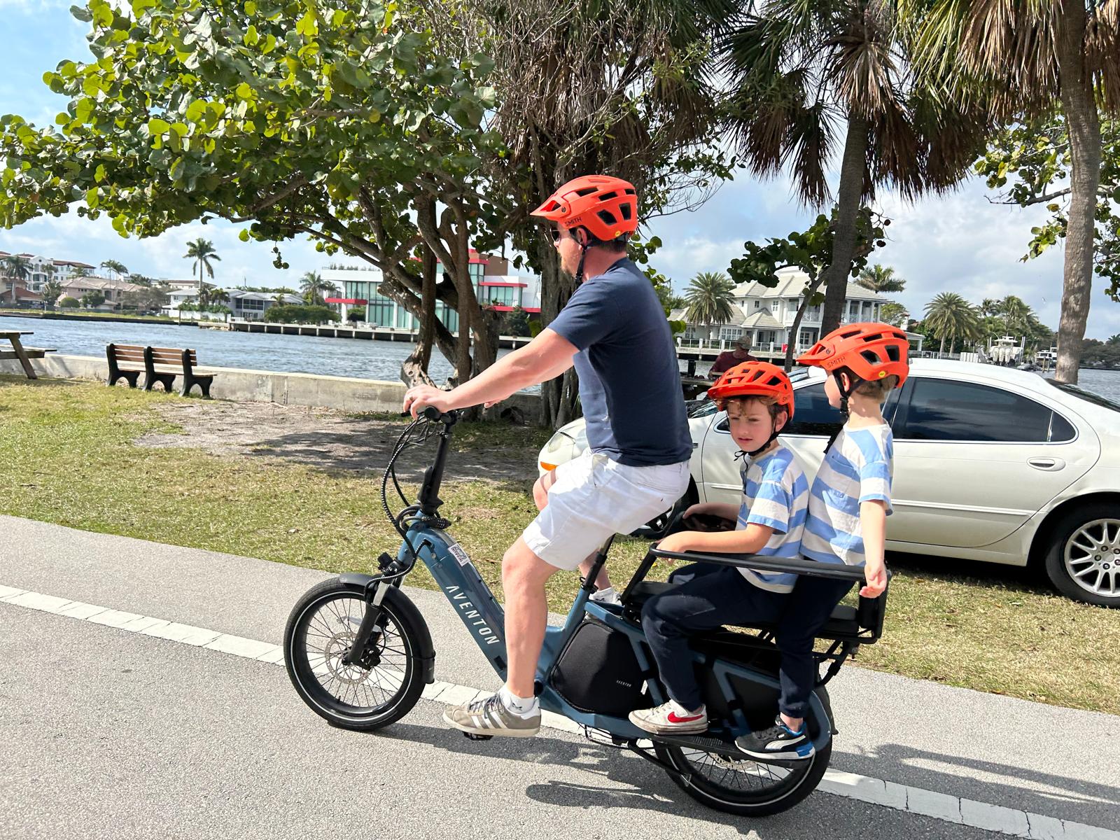 Dad riding an Aventon cargo eBike with two kids along the Fort Lauderdale intracoastal